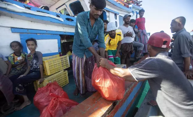 A Rohingya man receives food delivered by local fishermen to their boat anchored in the waters near the coast of Labuhan Haji, Aceh province, Indonesia, Tuesday, Oct. 22, 2024. (AP Photo/Binsar Bakkara)