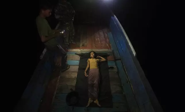 A young girl lies on the deck of a boat carrying Rohingya Muslims as she waits for a paramedic to check on her condition in the waters near the coast of Labuhan Haji, Aceh province, Indonesia, Tuesday, Oct. 22, 2024. (AP Photo/Binsar Bakkara)