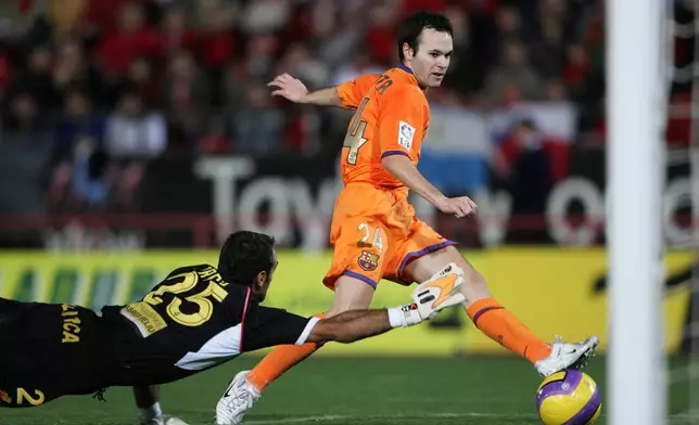 FILE - Barcelona's Andres Iniesta, right, scores against RCD Mallorca goalkeeper Antoni Prats during their Spanish League soccer match at Son Moix Stadium in the Balearic island of Mallorca, Spain, on Nov. 19, 2006. Andres Iniesta who scored Spain's World Cup-winning goal in 2010 and was one of the key players who made Barcelona's tiki-taka thrive for so long, announced his retirement from soccer on Tuesday. (AP Photo/Bernat Armangue, File)