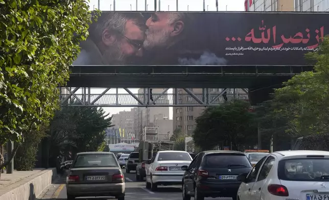 Vehicles drive past a billboard showing the late Iranian Revolutionary Guard Gen. Qassem Soleimani, who was killed in Iraq in a U.S. drone attack in 2020, kissing forehead of slain Hezbollah leader Hassan Nasrallah, in Tehran, Iran, Saturday, Oct. 5, 2024. (AP Photo/Vahid Salemi)