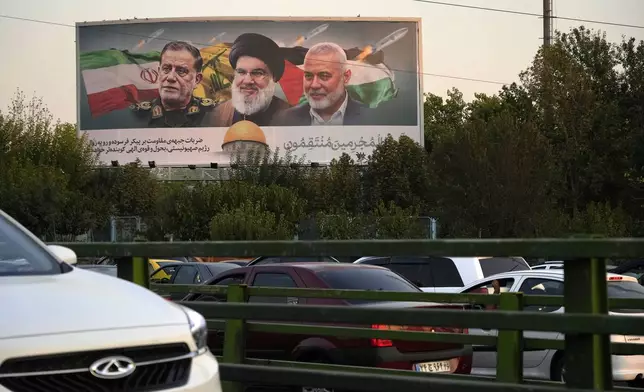 Vehicles drive past a billboard on a highway in Tehran, Iran, Monday, Oct. 7, 2024, showing slain Hezbollah leader Hassan Nasrallah, center, late Hamas leader Ismail Haniyeh, right, and the late Iranian Revolutionary Guard Gen. Abbas Nilforushan, who was killed in an Israeli airstrike. The billboard contains a verse of Quran that reads: "We will surely inflict punishment upon the wicked." (AP Photo/Vahid Salemi)