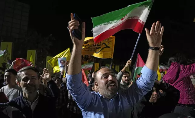 Demonstrators cheer as they wave Iranian and Hezbollah flags in an anti-Israeli gathering celebrating Iran's missile strike against Israel, at Felestin (Palestine) Sq. in Tehran, Iran, Tuesday, Oct. 1, 2024. (AP Photo/Vahid Salemi)