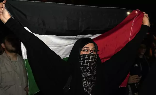 A demonstrator holds a Palestinian flag during an anti-Israeli gathering celebrating Iran's missile strike against Israel in front of the British Embassy in Tehran, Iran, Tuesday, Oct. 1, 2024. (AP Photo/Vahid Salemi)