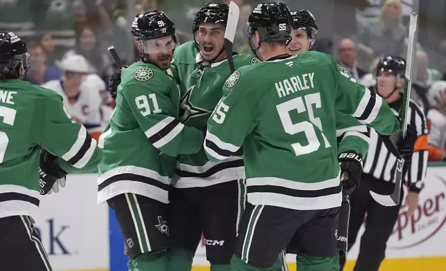 Dallas Stars center Tyler Seguin (91) hugs teammate Mason Marchment (27) to celebrate his goal with teammates Thomas Harley (55) and Esa Lindell (23) during the first period of an NHL hockey game against the New York Islanders Saturday, Oct. 12, 2024, in Dallas. (AP Photo/LM Otero)