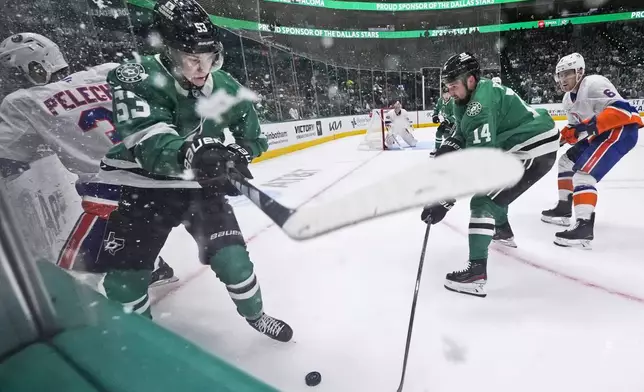 Dallas Stars center Wyatt Johnston (53) and New York Islanders defenseman Adam Pelech (3) play the puck as Stars left wing Jamie Benn (14) and Islanders defenseman Ryan Pulock (6) reach in during the first period of an an NHL hockey game Saturday, Oct. 12, 2024, in Dallas. (AP Photo/LM Otero)