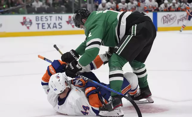 New York Islanders center Jean-Gabriel Pageau (44) is knocked to the ice by Dallas Stars left wing Jamie Benn, top, during the first period of an an NHL hockey game Saturday, Oct. 12, 2024, in Dallas. (AP Photo/LM Otero)