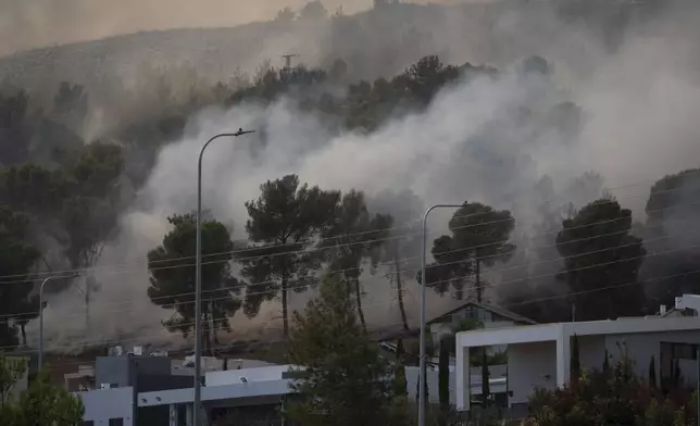 Smoke rises to the sky as fire burns in a site next to houses after a rocket, fired from Lebanon, hit a location near the town of Rosh Pinna, northern Israel, Sunday, Oct. 20, 2024. (AP Photo/Leo Correa)