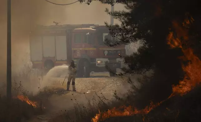 A firefighter works to extinguish a fire after a rocket, fired from Lebanon, hit an area near the town of Rosh Pinna, northern Israel, Sunday, Oct. 20, 2024. (AP Photo/Leo Correa)