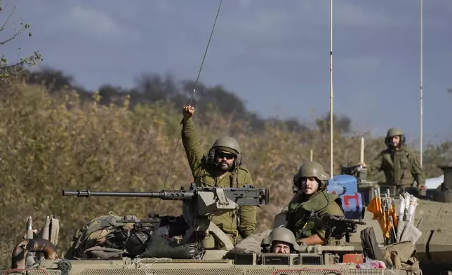 An Israeli soldier raises his fist from a moving APC in northern Israel near the Israel-Lebanon border, Tuesday, Oct. 1, 2024. (AP Photo/Baz Ratner)