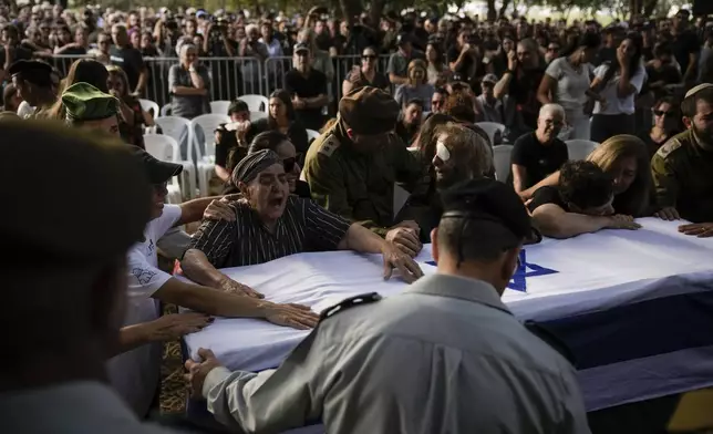 People mourn over the flagged-covered coffin of Israeli soldier Sgt. Amitai Alon, killed by a Hezbollah drone attack, during his funeral near Ramot Naftali, Israel, Monday, Oct. 14, 2024. (AP Photo/Leo Correa)