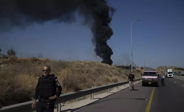 A Israeli police officer walks past site of a fire after a rocket, fired from Lebanon, hit an area near the town of Rosh Pinna, northern Israel, Sunday, Oct. 20, 2024. (AP Photo/Leo Correa)