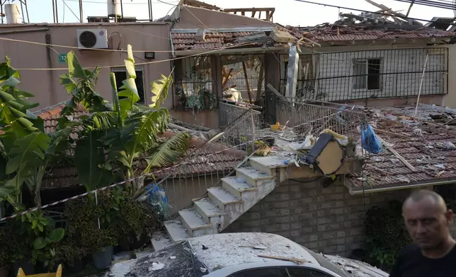 A member of Israeli security forces surveys damage to a home struck by a rocket fired from Lebanon in the town of Majd al-Krum, northern Israel, Wednesday, Oct. 16, 2024. (AP Photo/Ariel Schalit)