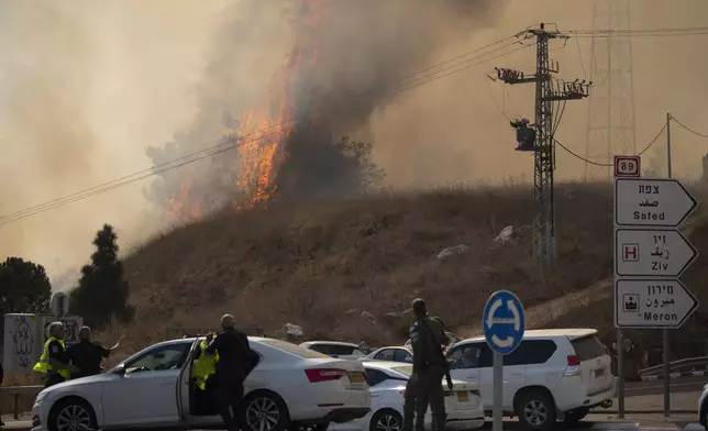 Members of the Israeli forces watch a fire after a rocket, fired from Lebanon, hit an area near the town of Rosh Pinna, northern Israel, Sunday, Oct. 20, 2024. (AP Photo/Leo Correa)