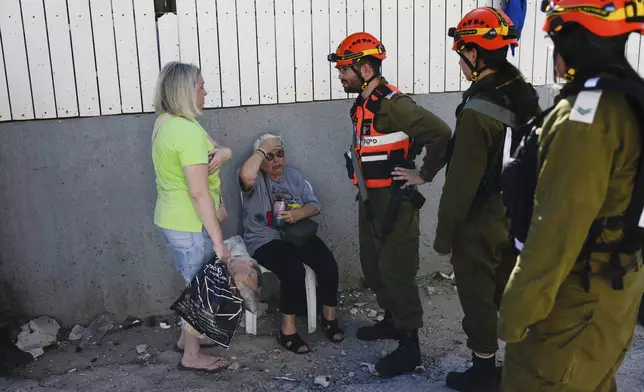 Israeli soldiers from the Homefront Command unit treat an elderly woman at the site that was hit by a rocket fired from Lebanon, in Kiryat Yam, northern Israel, on Tuesday, Oct. 8, 2024. (AP Photo/Ariel Schalit)