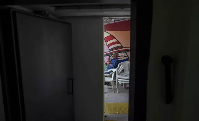 A man speaks on the phone in a public bomb shelter to stay safe from rockets fired from Lebanon in Acre, northern Israel, Sunday, Oct. 13, 2024. (AP Photo/Ariel Schalit)