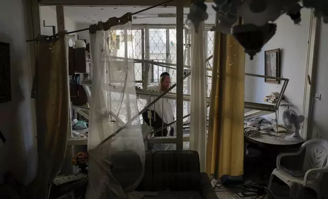 A man examine his damaged apartment that was hit by a rocket fired from Lebanon, in Kiryat Yam, northern Israel, on Tuesday, Oct. 8, 2024. (AP Photo/Ariel Schalit)