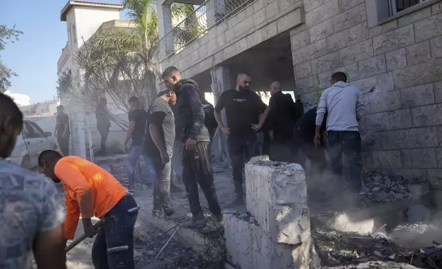 People examine a damaged house where one person was killed after a projectile launched from Lebanon slammed into Maalot-Tarshiha, northern Israel, Tuesday, Oct. 29, 2024. (AP Photo/Ohad Zwigenberg)