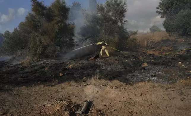 An Israeli firefighter works to extinguish a fire after a rocket fired from Lebanon hit near Nahariya, northern Israel, Monday, Sept. 30, 2024. (AP Photo/Baz Ratner)