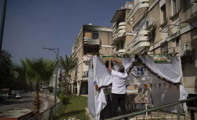 Zavik Zoigi checks the Sukkah, a temporary hut built for the Jewish holiday of Sukkot, placed in front of his residence ahead the weeklong holiday celebrations in Kiryat Shmona, a town located neart to the border with Lebanon, in northern Israel, Tuesday, Oct. 15, 2024. (AP Photo/Leo Correa)