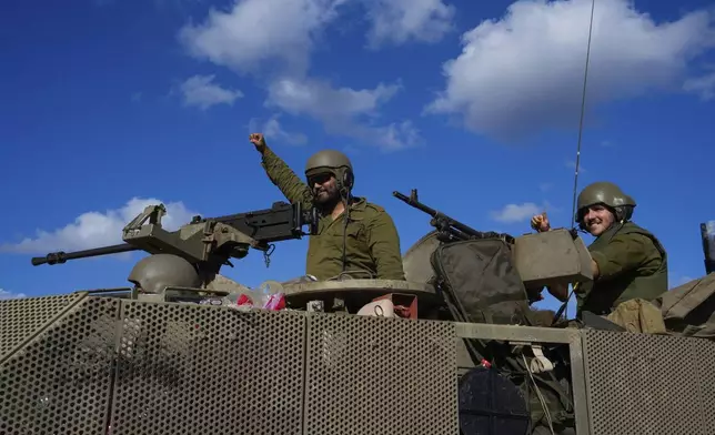 Israeli soldiers raise their fists from a moving APC in northern Israel near the Israel-Lebanon border, Tuesday, Oct. 1, 2024. (AP Photo/Baz Ratner)