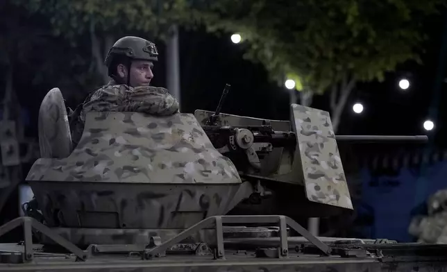 FILE - A Lebanese army soldier sits behind his weapon on the top of an armored personnel carrier at the site of an Israeli airstrike in Beirut's southern suburb, on Sept. 23, 2024. (AP Photo/Bilal Hussein, File)