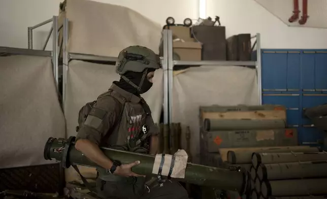 An Israeli soldier from an EOD (explosive ordnance disposal) unit moves a weapon used by Hezbollah seized during combat operations in Lebanon displayed during a government-organized media tour on a base in southern Israel, Wednesday, Oct. 9, 2024. (AP Photo/Maya Alleruzzo)