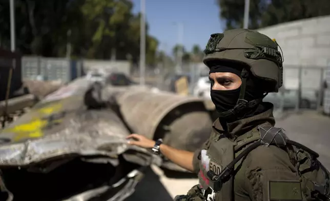 An Israeli soldier from an EOD (explosive ordnance disposal) unit gestures to Iranian ballistic missile components that were fired at Israel, during a government-organized media tour on a base in southern Israel, Wednesday, Oct. 9, 2024. (AP Photo/Maya Alleruzzo)