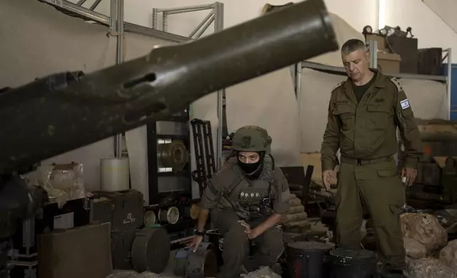 An Israeli soldier from an EOD (explosive ordnance disposal) unit, left, and an officer from the Israel Defense Forces Spokesperson's Unit walk through weapons used by Hezbollah seized during combat operations in Lebanon displayed during a government-organized media tour on a base in southern Israel, Wednesday, Oct. 9, 2024. (AP Photo/Maya Alleruzzo)