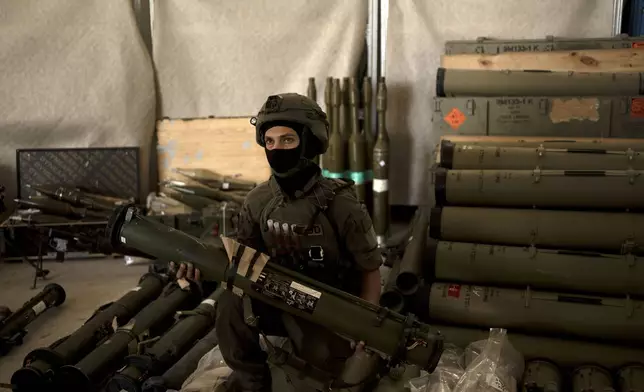 An Israeli soldier from an EOD (explosive ordnance disposal) poses with a weapon used by Hezbollah seized during combat operations in Lebanon displayed during a government-organized media tour on a base in southern Israel, Wednesday, Oct. 9, 2024. (AP Photo/Maya Alleruzzo)