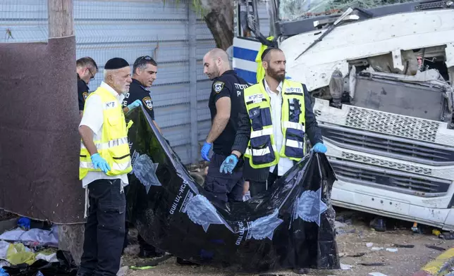 Israeli police and rescue services inspect the body of a truck driver that rammed into a bus stop near the headquarters of Israel's Mossad spy agency, wounding dozens of people, according to Israel's Magen David Adom rescue service in Tel Aviv, Israel, Sunday, Oct. 27, 2024. (AP Photo/Ohad Zwigenberg)