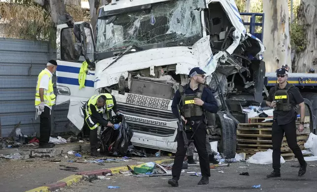 Israeli police and rescue services inspect the site where a truck driver rammed into a bus stop near the headquarters of Israel's Mossad spy agency, wounding dozens of people, according to Israel's Magen David Adom rescue service in Tel Aviv, Israel, Sunday, Oct. 27, 2024. (AP Photo/Oded Balilty)