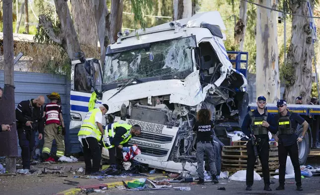 Israeli police and rescue services inspect the site where a truck driver rammed into a bus stop near the headquarters of Israel's Mossad spy agency, wounding dozens of people, according to Israel's Magen David Adom rescue service in Tel Aviv, Israel, Sunday, Oct. 27, 2024. (AP Photo/Ohad Zwigenberg)