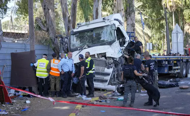 Israeli police and rescue services inspect the body of a truck driver that rammed into a bus stop near the headquarters of Israel's Mossad spy agency, wounding dozens of people, according to Israel's Magen David Adom rescue service in Tel Aviv, Israel, Sunday, Oct. 27, 2024. (AP Photo/Ohad Zwigenberg)