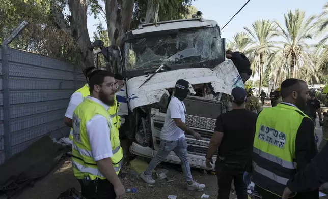 Israeli police and rescue services inspect the site where a truck driver rammed into a bus stop near the headquarters of Israel's Mossad spy agency, wounding dozens of people, according to Israel's Magen David Adom rescue service in Tel Aviv, Israel, Sunday, Oct. 27, 2024. (AP Photo/Oded Balilty)