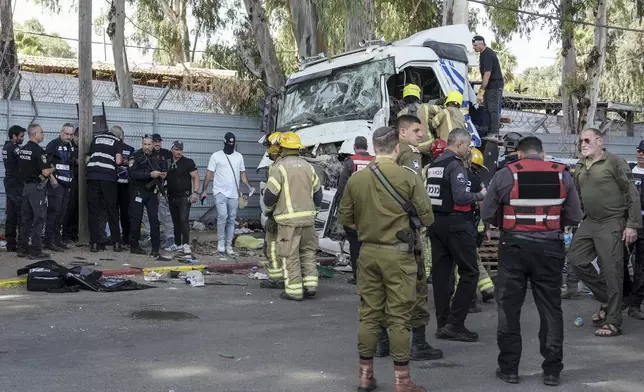 Israeli police and rescue workers climb on a truck to inspect the body of a driver that rammed into a bus stop near the headquarters of Israel's Mossad spy agency, wounding dozens of people, according to Israel's Magen David Adom rescue service in Tel Aviv, Israel, Sunday, Oct. 27, 2024. (AP Photo/Oded Balilty)