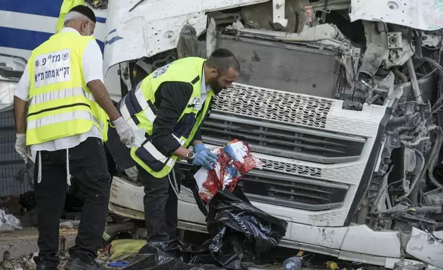 Members of Zaka Rescue and Recovery team work where a truck driver rammed into a bus stop near the headquarters of Israel's Mossad spy agency, wounding dozens of people, according to Israel's Magen David Adom rescue service in Tel Aviv, Israel, Sunday, Oct. 27, 2024. (AP Photo/Oded Balilty)