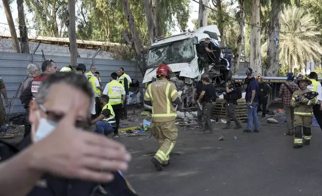 Israeli police and rescue services inspect the body of a truck driver that rammed into a bus stop near the headquarters of Israel's Mossad spy agency, wounding dozens of people, according to Israel's Magen David Adom rescue service in Tel Aviv, Israel, Sunday, Oct. 27, 2024. (AP Photo/Oded Balilty)