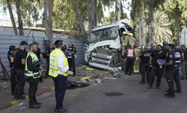 Israeli police and rescue workers climb on a truck to inspect the body of a driver that rammed into a bus stop near the headquarters of Israel's Mossad spy agency, wounding dozens of people, according to Israel's Magen David Adom rescue service in Tel Aviv, Israel, Sunday, Oct. 27, 2024. (AP Photo/Oded Balilty)