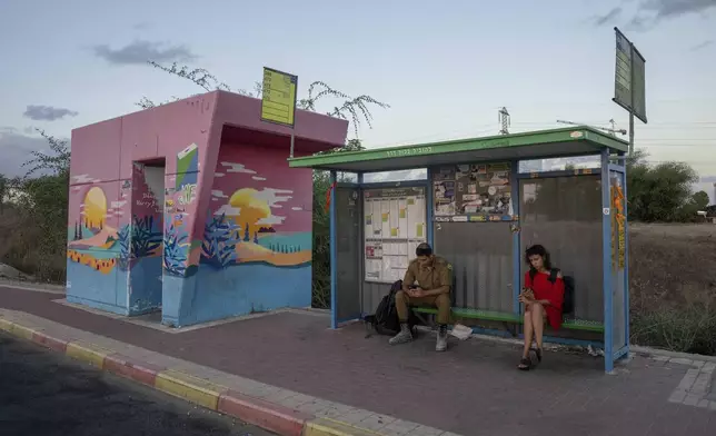 A soldier and a woman wait at a bus stop next to a bomb shelter in the town of Sderot, southern Israel, Monday, Sept. 16, 2024. (AP Photo/Ohad Zwigenberg)