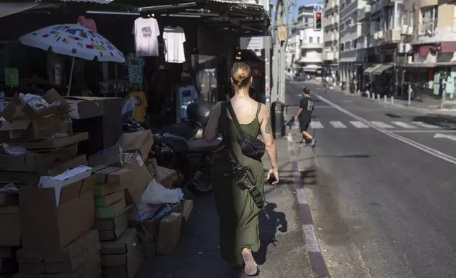 An off-duty Israeli soldier carrying her M-16 rifle walks down the street in Tel Aviv Israel, Friday, Sept. 27, 2024. (AP Photo/Ohad Zwigenberg)