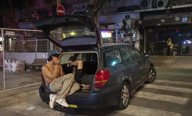 Young people chat in the rear of a car in Tel Aviv, Israel, Wednesday, Sept. 25, 2024. (AP Photo/Ohad Zwigenberg)