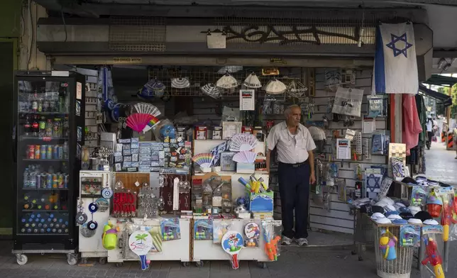 A man stands at the entrance to his empty souvenir shop in the Carmel market in Tel Aviv, Israel, on Wednesday, Sept. 25, 2024. (AP Photo/Ohad Zwigenberg)