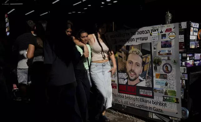 People walk next to the market stand belonging to Elkana Bohbot, who was kidnapped from the Nova festival and has not been released from Gaza in the Carmel Market in Tel Aviv, Israel, Sept. 27, 2024.(AP Photo/Ohad Zwigenberg)