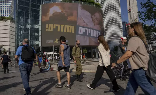 People pass by a sign calling for the release of hostages held in the Gaza Strip by Hamas for nearly a year, in Tel Aviv, Israel, Monday, Sept. 10, 2024. (AP Photo/Ohad Zwigenberg)