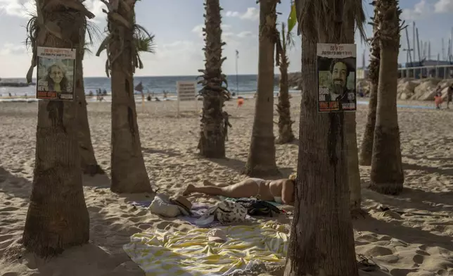 Signs calling for the release of hostages held in the Gaza Strip are plastered on trees in Tel Aviv's beach, Israel, Saturday, Sept. 14, 2024. (AP Photo/Ohad Zwigenberg)