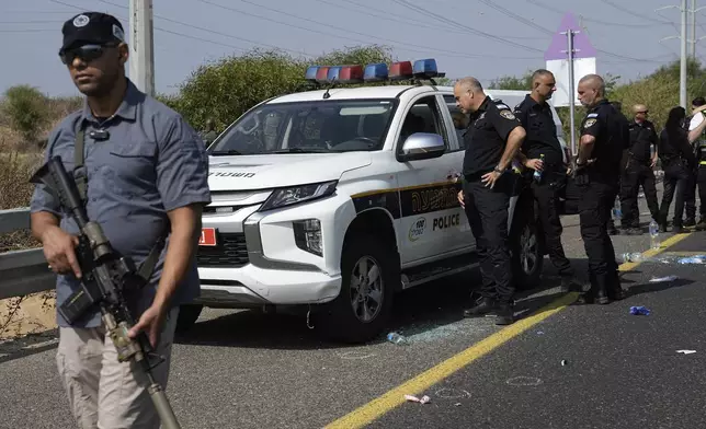 Israeli security forces examine the scene of a shooting attack where they said a police officer was killed and several others were wounded near Yavne, Israel, Tuesday, Oct. 15, 2024. (AP Photo/Tsafrir Abayov)