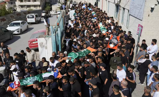 Draped in the Palestinian, Hamas and Islamic Jihad flags, mourners carry the bodies of 18 Palestinians who were killed in an Israeli airstrike during their funeral in Tulkarem, Friday, Oct. 4, 2024. (AP Photo/Nasser Nasser)