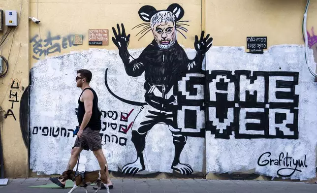 People pass by a newly painted graffiti depicting Hamas Leader Yahya Sinwar, days after he was killed by Israeli forces in Gaza, in Tel Aviv, Israel, on Sunday, Oct. 20, 2024. (AP Photo/Oded Balilty)