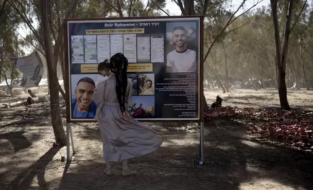 A woman reads a memorial poster at the site of the Nova music festival, where hundreds of revelers were killed or kidnapped by Hamas, on the Jewish holiday of Simchat Torah, marking one year in the Hebrew calendar since the attack, near Kibbutz Re'im, southern Israel near the Gaza Strip, Thursday, Oct. 24, 2024. (AP Photo/Maya Alleruzzo)