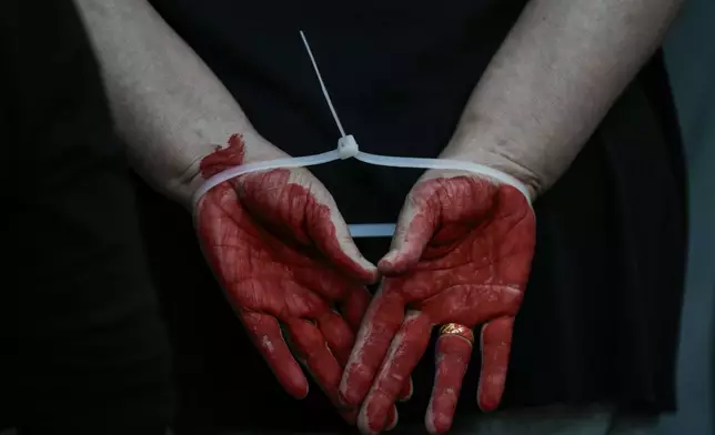 A woman demonstrator takes part in a performance calling for the release of hostage Naama Levy, held in the Gaza Strip by the Hamas militant group, in Tel Aviv, Israel, Saturday, Oct. 19, 2024. (AP Photo/Mahmoud Illean)